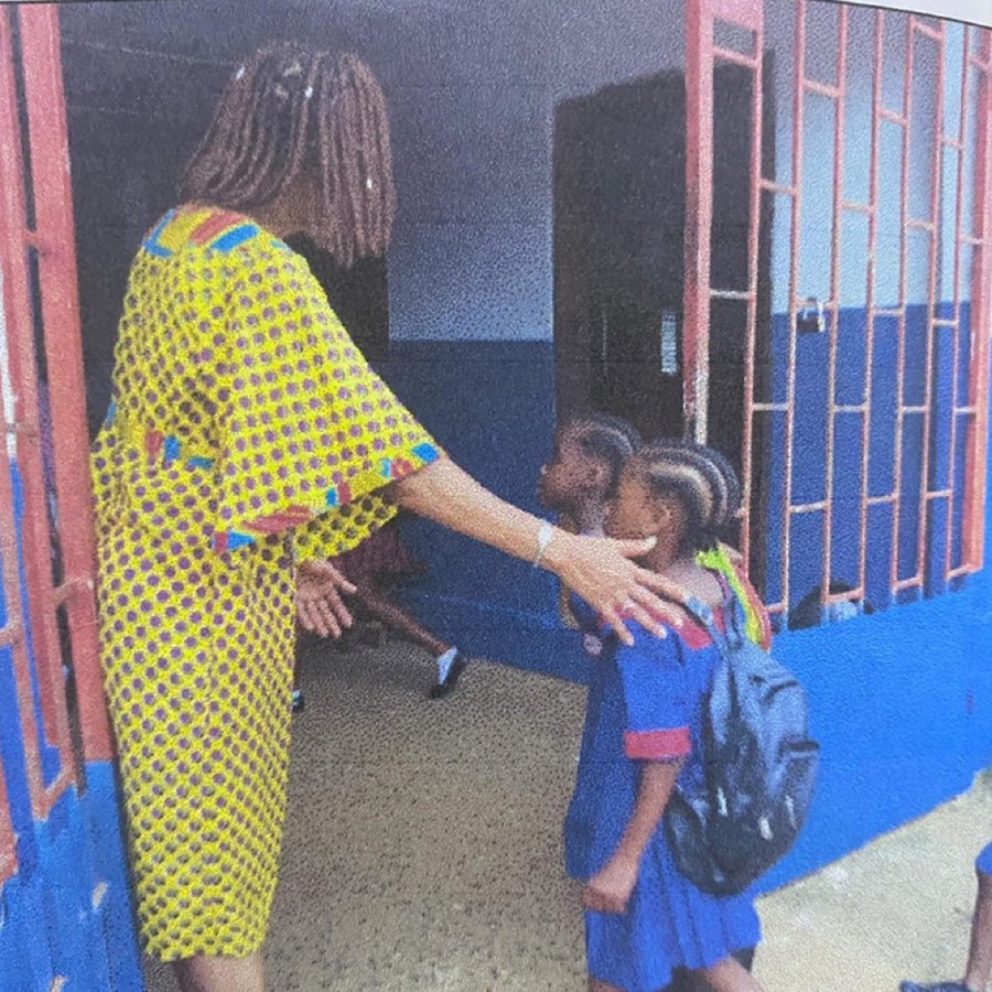 A member of staff welcoming two young pupils at the school entrance