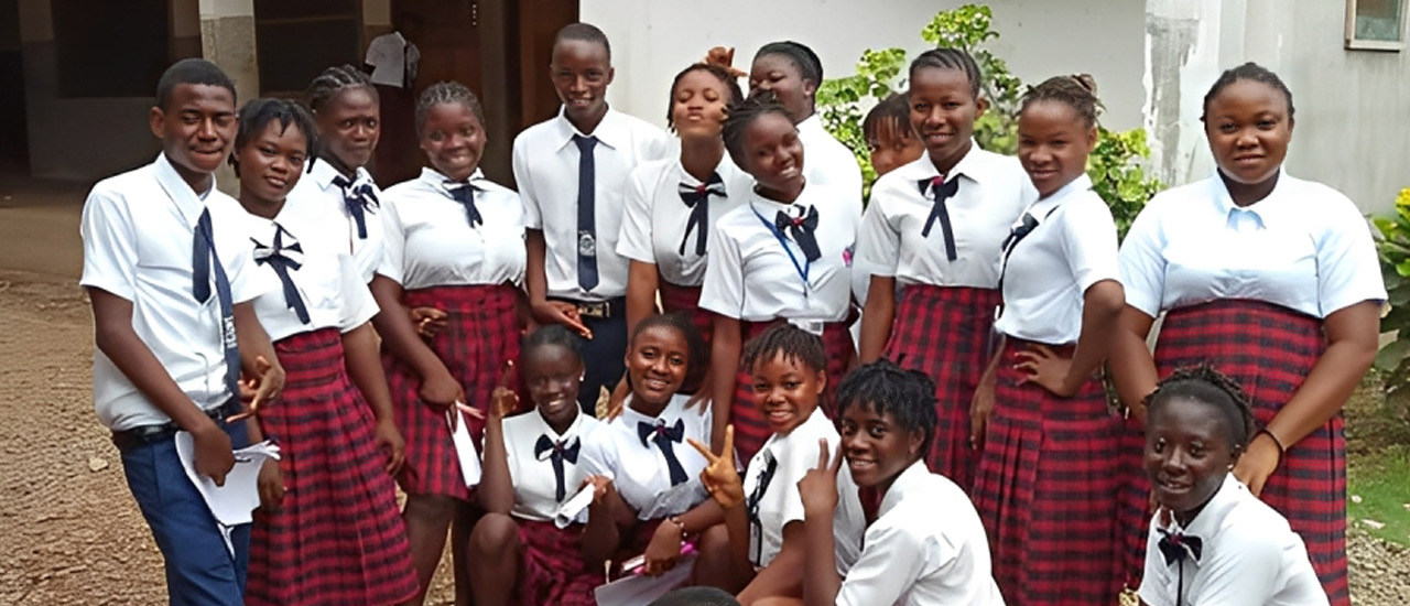 Senior pupils in KFI uniform gathered together outside the school building