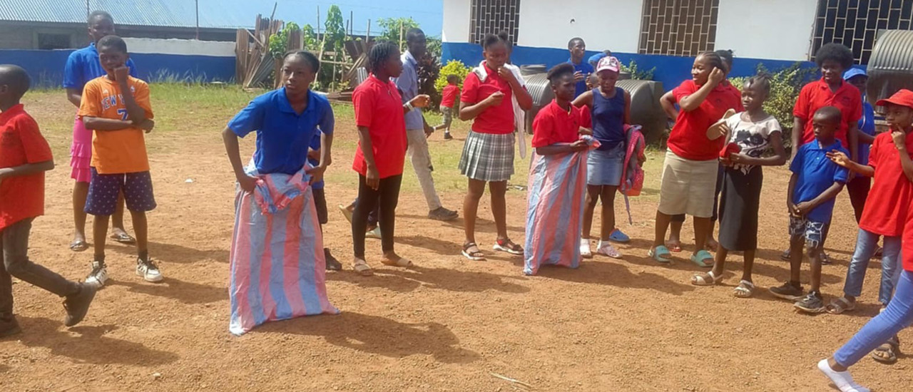Pupils taking part in a sack race on the school field during sports day, watched by classmates